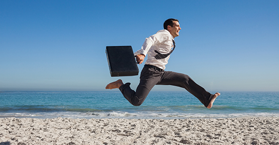 Business man on the beach jumping
