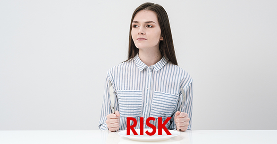 Young woman sitting with the word RISK on a plate