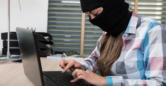 Female wearing ski mask using computer.