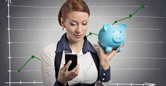 Woman holding piggy bank and looking at cell phone