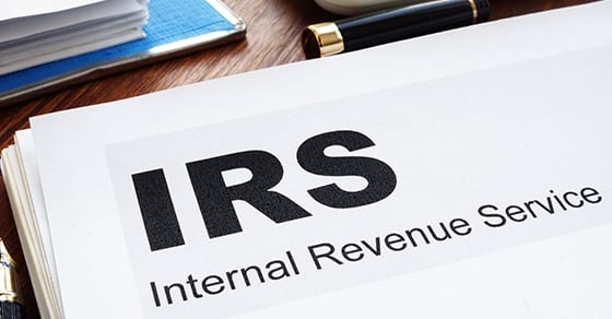 A stack of papers, the top one of which reads "IRS Internal Revenue Service" in large letters