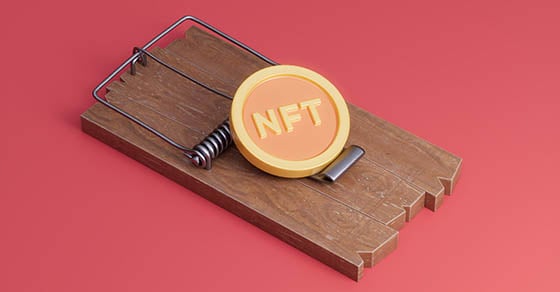 A mouse trap on a red surface with a yellow NFT coin sitting on top of it.
