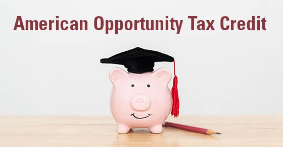 A pink piggy bank with a graduation cap on it sitting on a wooden table top. The words "American Opportunity Tax Credit" are above it in dark red.