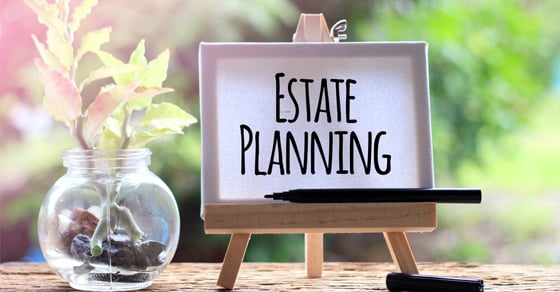 A wooden desk with a plant and a sign on it, the sign reads "Estate Planning".