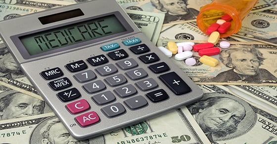 A calculator that reads "Medicare" and a bottle of medication sitting on top of money.