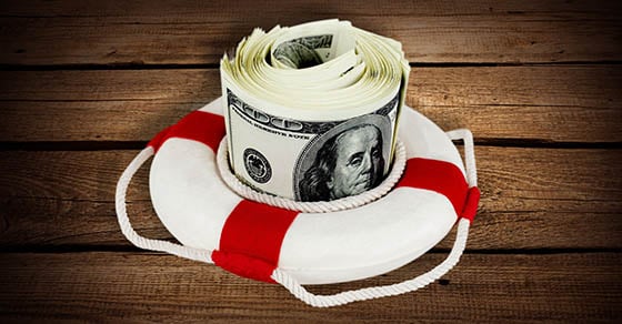A large amount of cash sitting inside of a lifebuoy on top of a wooden paneled surface.