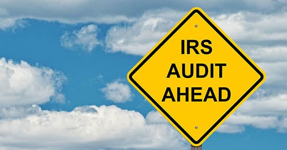 A yellow diamond street sign that reads "IRS Audit Ahead".