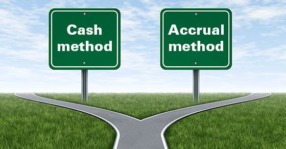 A fork in the road, one side has a sign that reads 'CASH METHOD', and the other side reads 'ACCRUAL METHOD'.