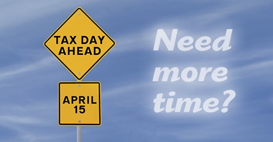 A yellow diamond street sign that reads 'TAX DAY AHEAD' with another square sign below it that says 'APRIL 15'. White text reading 'NEED MORE TIME?' is to the right of the sign, overlaying a blue sky background image.