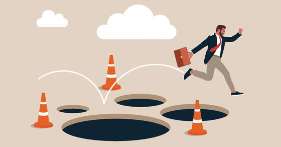An illustration of a business man jumping over potholes with cones around them.