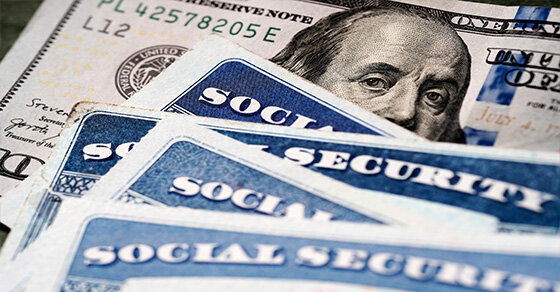 A few social security cards stacked on top of some $100 bills.