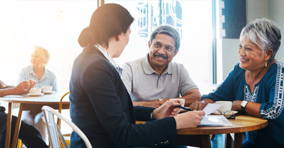 Three people chatting and smiling while sitting together at a table.