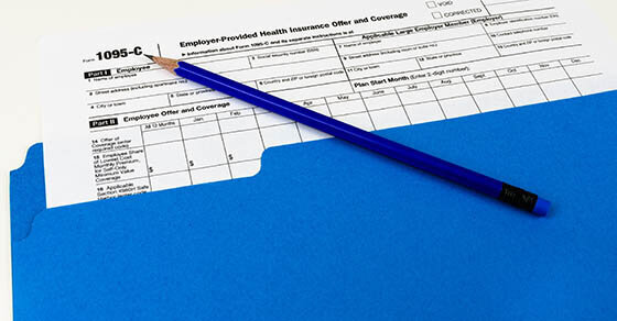 A blue folder with a tax form sticking halfway out of it with a blue pencil sitting on top.