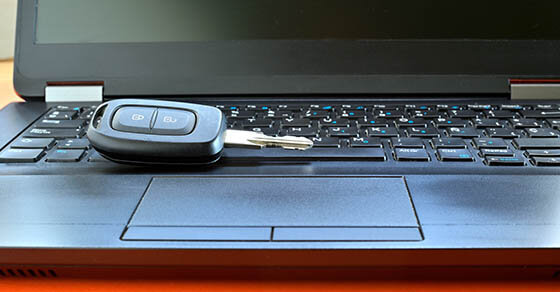 A car key sitting on the keyboard of a laptop.