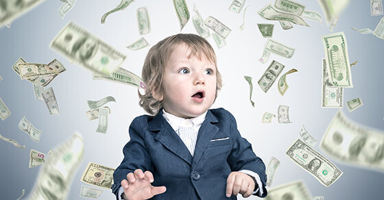 A child in business wear with money falling down all around them.